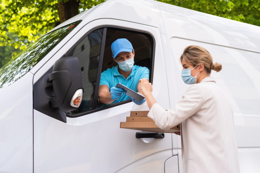 Safe delivery - courier on a van brings a pizza to the client