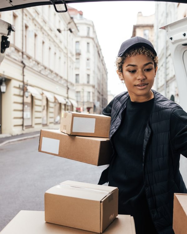 Delivery worker unloading cardboard boxes while standing at van trunk