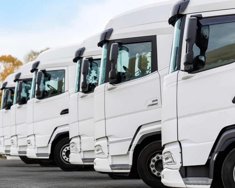 Fleet of new modern electric hybrid hydrogen or diesel white trucks parked in line row outdoors